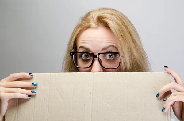 Женщина подглядывает через край пустой бумажный рекламный щит — стоковое фото