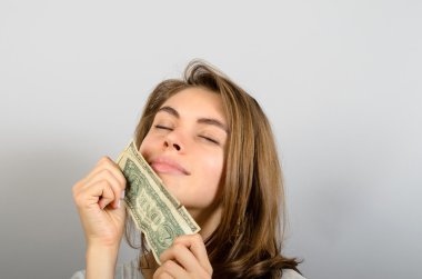 Doları banknot sıkıca tutan portre portre açgözlü genç kadın gri duvar arka plan izole