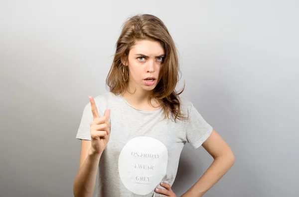 portre ciddi, çatık, kızgın, birisi azar grumpyyoung kadın işaret parmağı yukarıya doğru gri arka plan izole