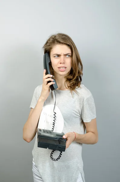 Mulher com escritório ou telefone doméstico. Em um fundo cinza . — Fotografia de Stock