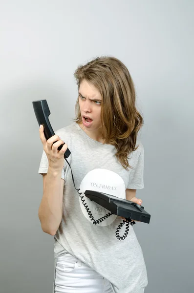 Mulher com escritório ou telefone doméstico. Em um fundo cinza . — Fotografia de Stock