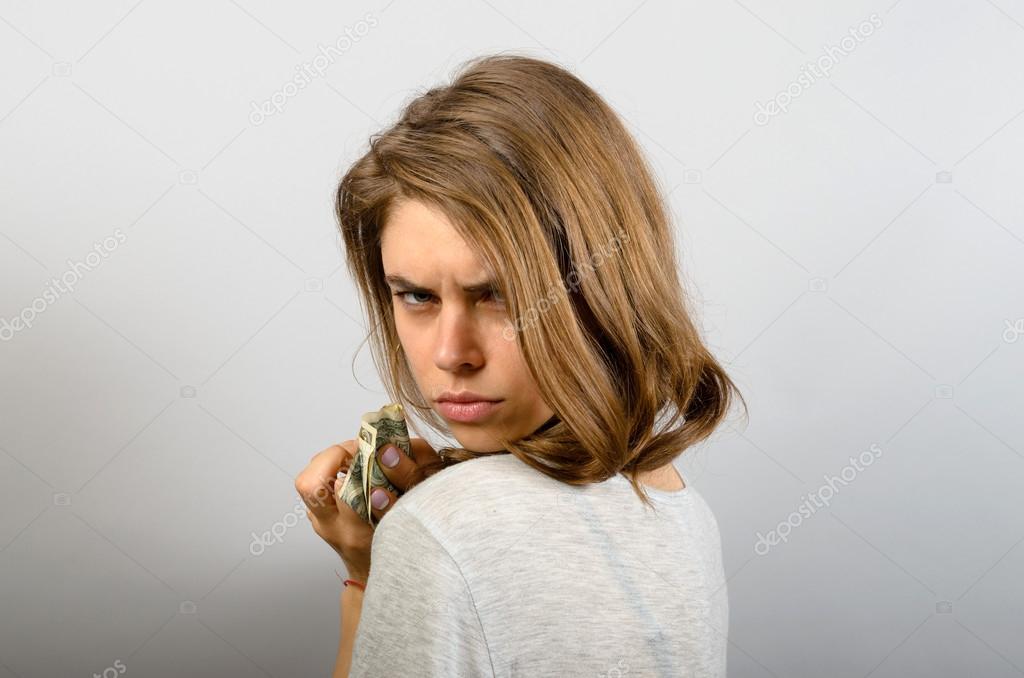 Closeup portrait greedy young woman  holding dollar banknotes tightly isolated grey wall background