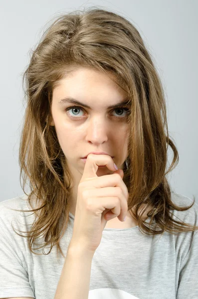 Mulher bonito pensa dedo perto da boca. Fundo cinzento . — Fotografia de Stock