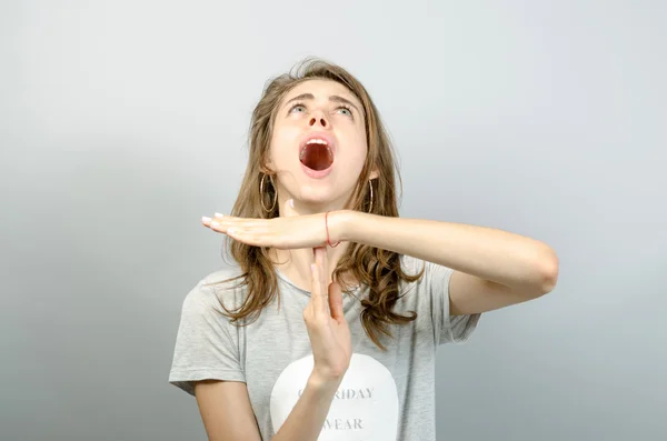 Mujer joven mostrando tiempo de espera. Sobre un fondo gris . — Foto de Stock