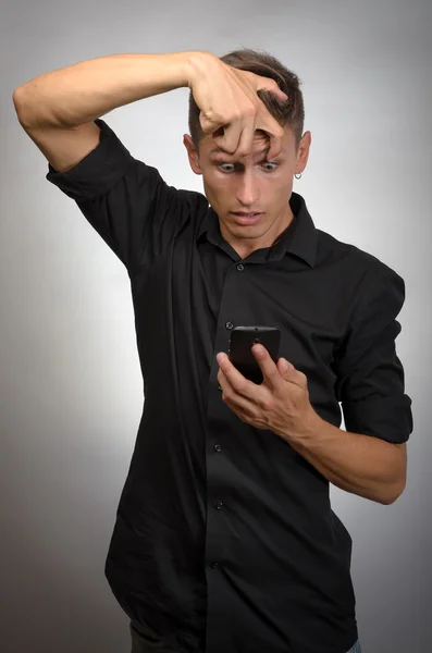 Nahaufnahme Porträt schläfriger, lustig aussehender junger Mann, Finger halten Augen offen, wenig Energie, versucht wach zu bleiben, Smartphone in der Hand — Stockfoto