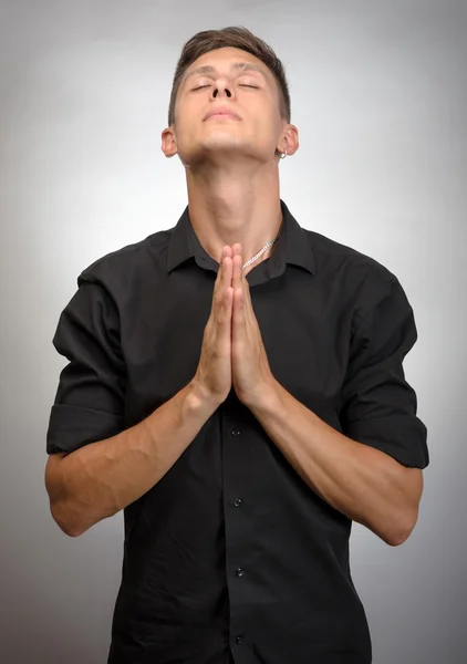 Closeup portrait young man praying hoping for best asking for forgiveness or miracle isolated gray wall background. — Stock Photo, Image