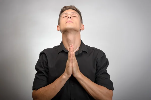 Nahaufnahme Porträt junger Mann betet in der Hoffnung auf das Beste um Vergebung bitten oder Wunder isoliert graue Wand Hintergrund. — Stockfoto