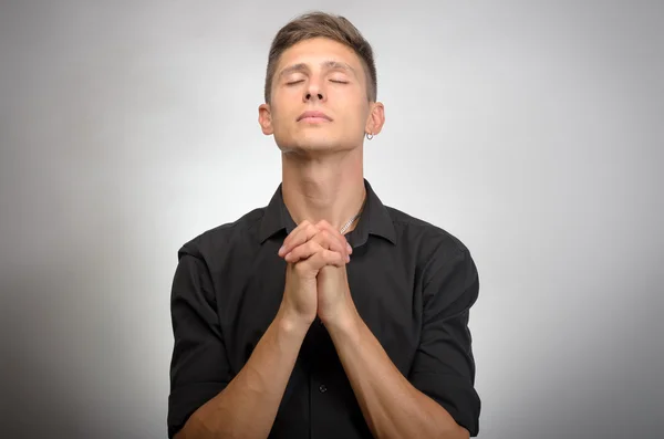 Nahaufnahme Porträt junger Mann betet in der Hoffnung auf das Beste um Vergebung bitten oder Wunder isoliert graue Wand Hintergrund. — Stockfoto
