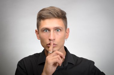 ağız, gri duvar arka plan üzerinde izole yakınındaki sakin parmak koymak istiyorsun adam