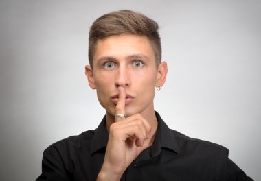 ağız, gri duvar arka plan üzerinde izole yakınındaki sakin parmak koymak istiyorsun adam