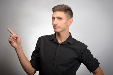 Kameraya bakarak ve sağ elinde, gri izole ile işaret eden genç işadamı