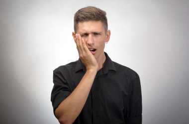 Genç bir adam diş ağrısı hisseder.