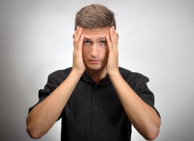 Adam çok yorgun, o elleriyle başını tutar. Gri arka planı