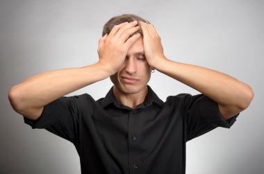 Adam çok yorgun, o elleriyle başını tutar. Gri arka planı