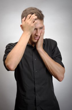 Adam çok yorgun, o elleriyle başını tutar. Gri arka planı