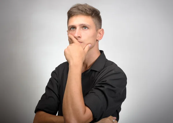 Joven guapo hombre dudando aislado sobre gris fondo — Foto de Stock