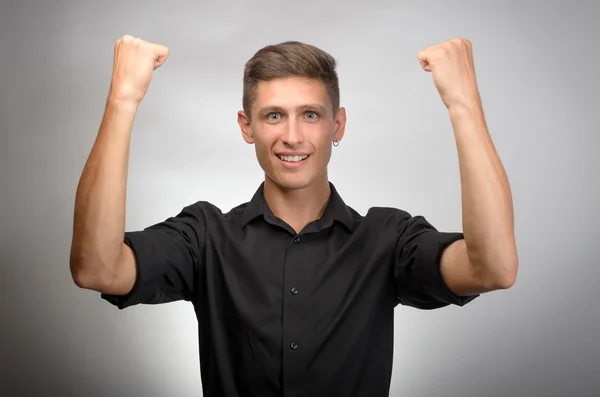 Feliz hombre de negocios celebrando su éxito sobre fondo gris. Mirando la cámara — Foto de Stock