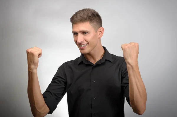 Feliz hombre de negocios celebrando su éxito sobre fondo gris. Mirando la cámara — Foto de Stock