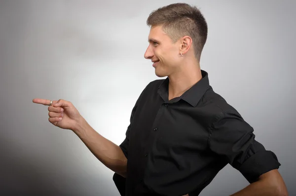 Joven hombre de negocios guapo apuntando a algo usando un dedo. Izquierda — Foto de Stock