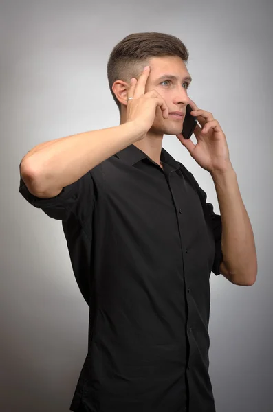Joven elegante hombre llamando por teléfono contra fondo gris — Foto de Stock