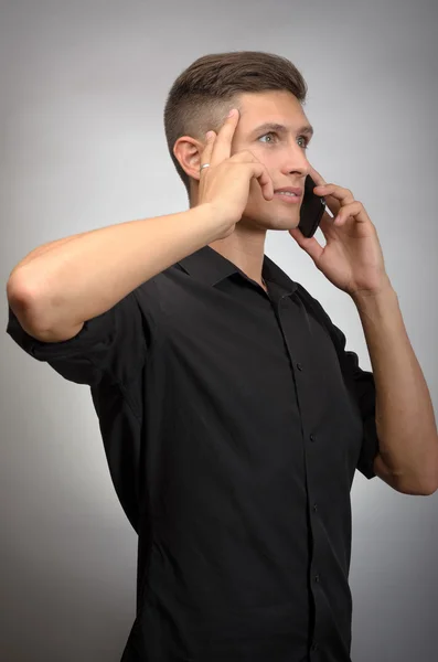 Joven elegante hombre llamando por teléfono contra fondo gris — Foto de Stock