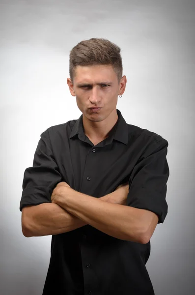 Retrato de un joven guapo de pie con los brazos cruzados sobre fondo gris — Foto de Stock