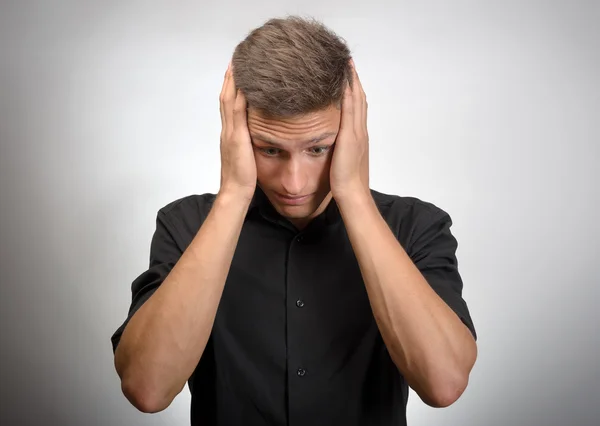 O homem realmente cansado, segura a cabeça com as mãos. Fundo cinzento — Fotografia de Stock