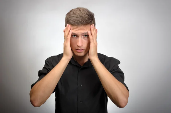 Adam çok yorgun, o elleriyle başını tutar. Gri arka planı