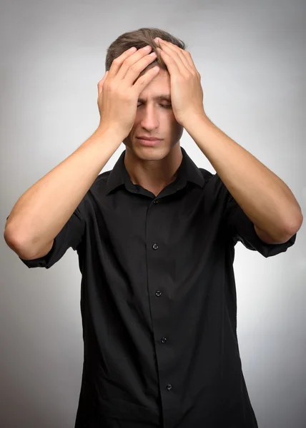 El hombre realmente cansado, sostiene su cabeza con las manos. Fondo gris —  Fotos de Stock