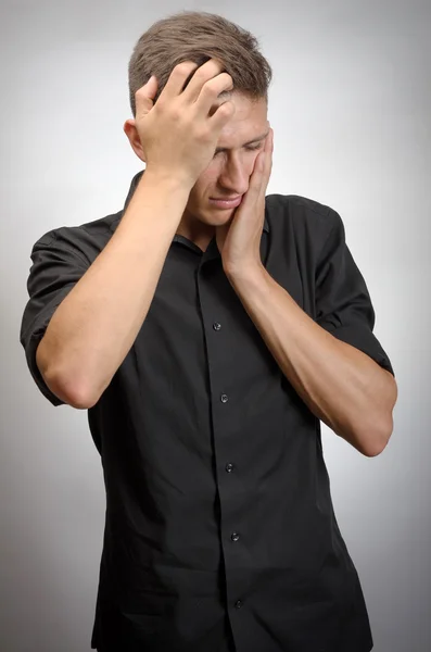 El hombre realmente cansado, sostiene su cabeza con las manos. Fondo gris —  Fotos de Stock