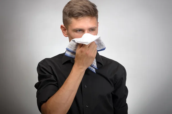 Młody człowiek cierpi na zimno, wieje jego nos — Zdjęcie stockowe