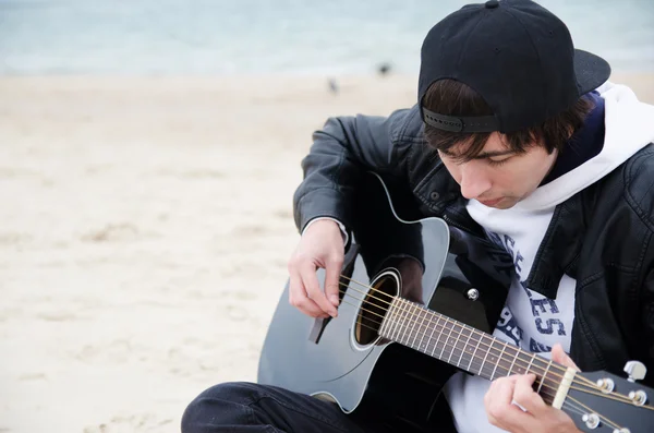 young man plays guitar at the beach