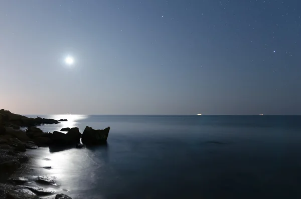 This photo illustration of a deep blue moonlit ocean at night with calm waves Royalty Free Stock Photos