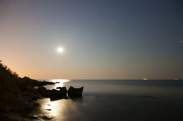 This photo illustration of a deep blue moonlit ocean at night with calm waves Stock Picture