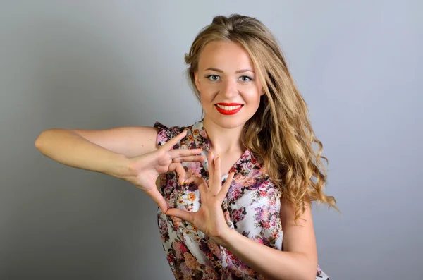 Jovem mulher atraente mostrando forma do coração com os dedos — Fotografia de Stock