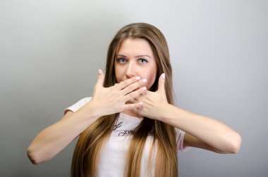 Oops! Ellerle ağız kapsayan ve kamera gri arka plan karşı dururken bakan sürpriz genç kadın