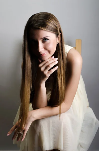 Hermosa mujer con un vestido sentado en una silla. Captura de estudio . —  Fotos de Stock