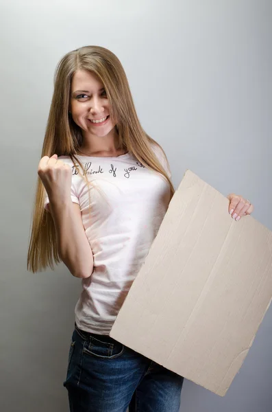 Hermosa mujer de pie detrás, sosteniendo pancarta de tablero en blanco, sobre fondo gris — Foto de Stock