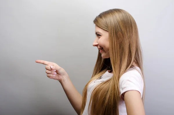 Mooie woman wijzend ergens, geïsoleerd op een grijze achtergrond — Stockfoto