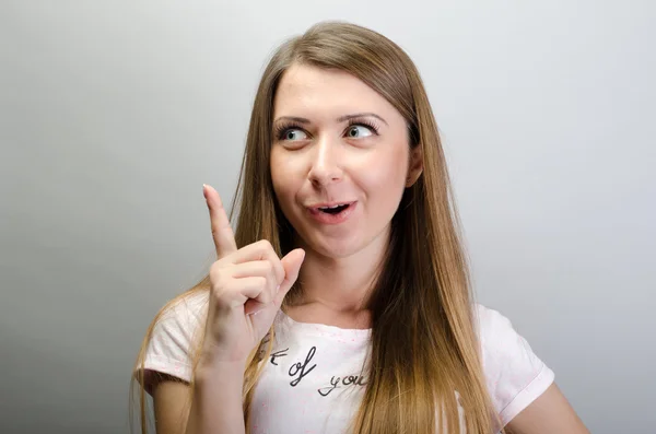 Retrato de una chica sonriente señalando con el dedo hacia arriba teniendo una idea —  Fotos de Stock