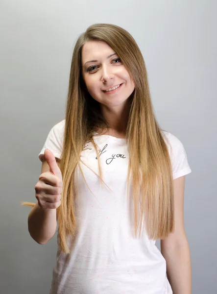 Retrato de una mujer alegre mostrando el pulgar hacia arriba sobre fondo gris — Foto de Stock