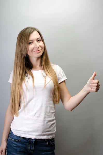 Retrato de una mujer alegre mostrando el pulgar hacia arriba sobre fondo gris —  Fotos de Stock