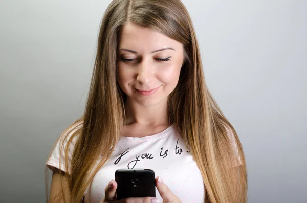 Молода красива жінка з мобільним телефонним розмовником, що вводить смс — стокове фото
