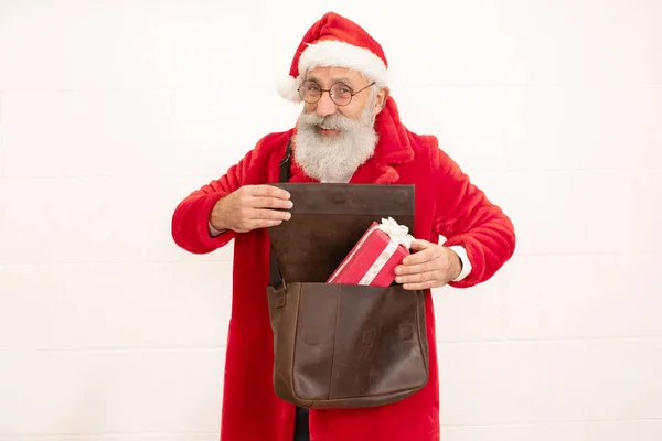 圣诞老人把礼物藏在装着白色背景的袋子里 — 图库照片