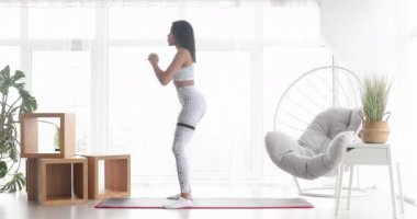 Spor yapan atletik siyah kadın elastik bantla esneme egzersizleri yapıyor, evde antrenman yapıyor. Sağlıklı bir yaşam tarzı. Fitness.