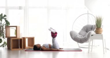 Spor kıyafetli güzel bir kadın. Ayak bileği ağırlığıyla egzersiz yapıyor. Evde covid-19 sırasında ağırlık antrenmanı yapıyor.. 