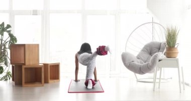 Spor kıyafetli güzel bir kadın. Ayak bileği ağırlığıyla egzersiz yapıyor. Evde covid-19 sırasında ağırlık antrenmanı yapıyor.. 