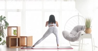 Spor yapan atletik siyah kadın çömelme egzersizleri yapıyor, evde antrenman yapıyor. Sağlıklı bir yaşam tarzı. Fitness.  