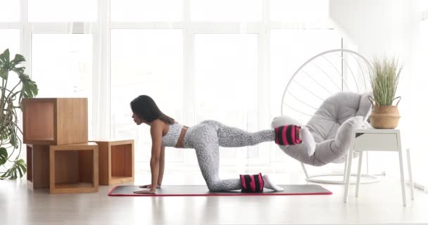 かなりフィットネス黒女性でスポーツウェア練習ロバキック運動で足首の重み強度トレーニングとともに自宅でCovid — ストック動画