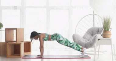 Konsantre olmuş ince, siyah kadın kalas egzersizi yapıyor. Kendinden emin Afro-Amerikan sporcu kadın eğitiminin portresi..